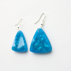 glittery blue resin triangle earrings with silver plated hooks. side view