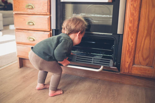 Toddler opening stove oven in kitchen