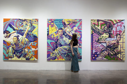 His wife, Ilana standing in a gallery in front of three large paintings he did for his Wushu series