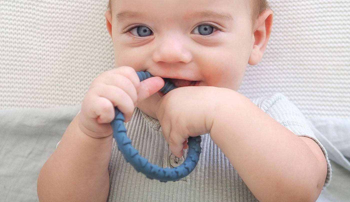 teething baby chewing on teething ring teether toy bracelet
