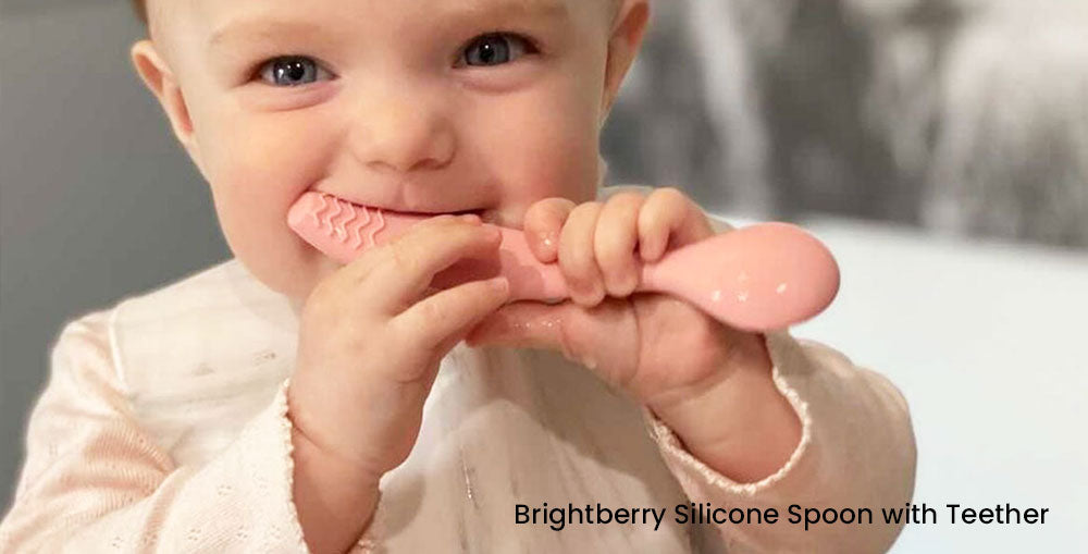 bébé fille faisant ses dents et apaisant les gencives douloureuses avec une cuillère de dentition en silicone Brightberry