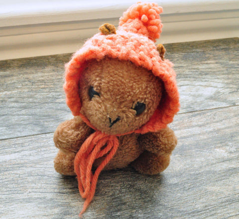 Squirrel stuffed animal with muted orange hand knit bonnet topped with tiny pom pom.