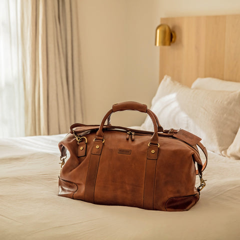 leather weekend bag on bed in a hotel room