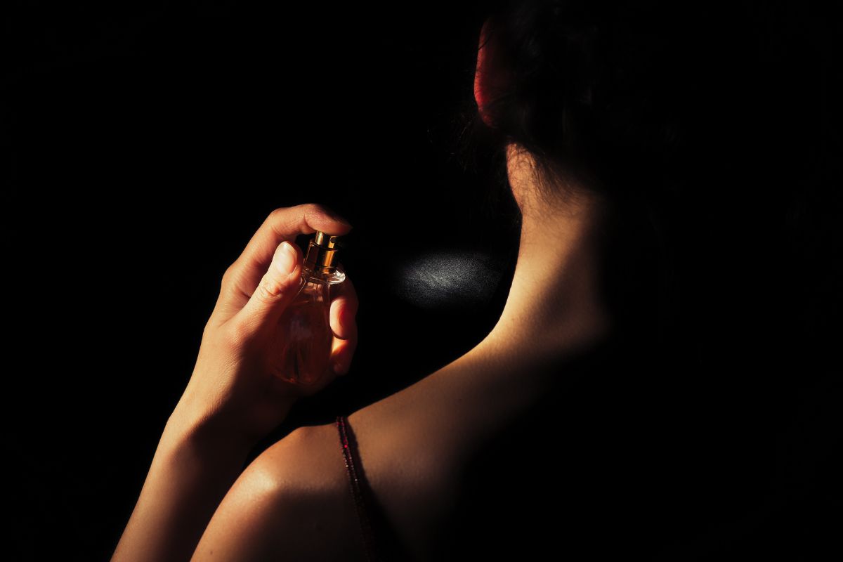 Woman spraying perfume on her neck.