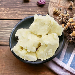 shea butter sitting in a bowl on top of a blue and white striped cloth