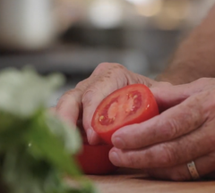 Hand holding a freshly sliced tomato