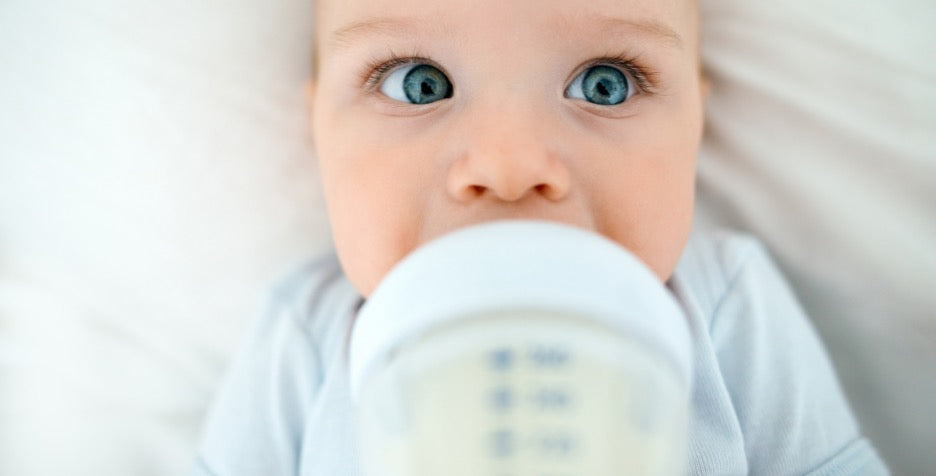 baby on sterilised feeding bottle