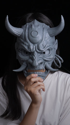 3Dプリントした鬼のマスクを顔の前に持つ女の子。