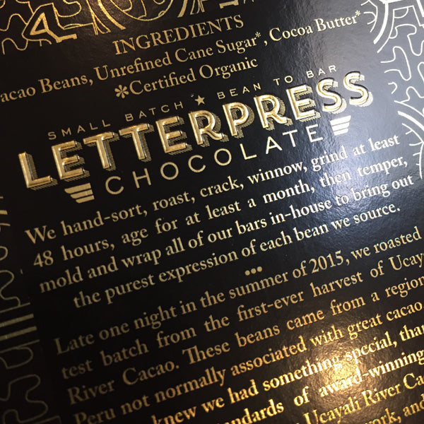 a closeup partial view of the back of the packaging, showing the embossed letterpress chocolate logo