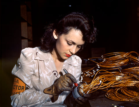 A vintage photograph of a woman working on aircraft parts