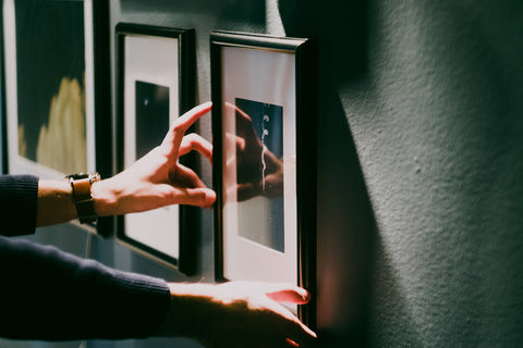 Photo of a person hanging a framed print on the wall