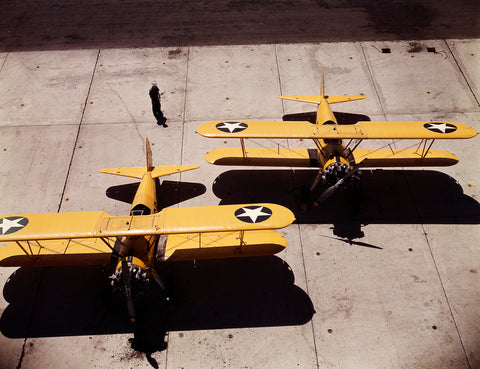 A vintage color photograph feauturing two yellow N2S planes