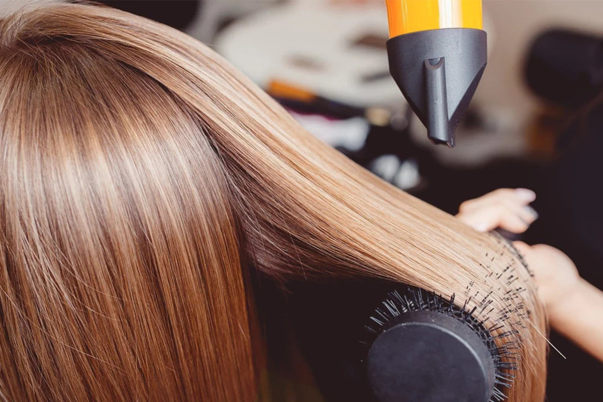 Image of a girl simultaneously blow drying and brushing her hair, achieving a smooth and styled look