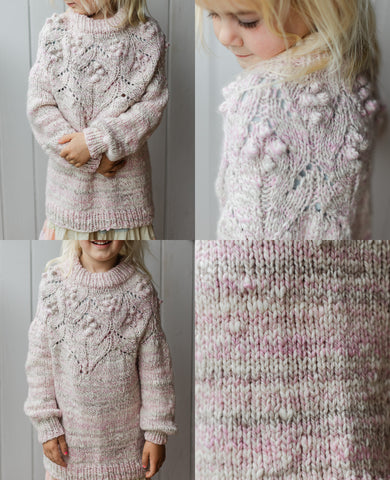 A little girl models a handspun and knit pink, grey and white sweater