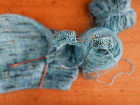 overview photo of sleeves being knit on copper circular knitting needles