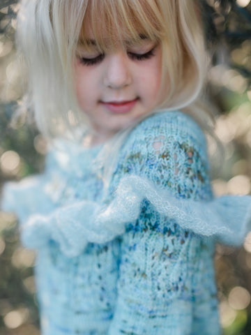 young girl modeling hand knit sweater in variegated blue and green yarn