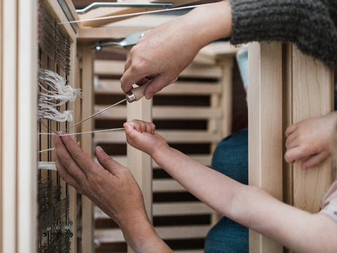 mother and daughter hands threading baby wolf loom aerial view - this darling home