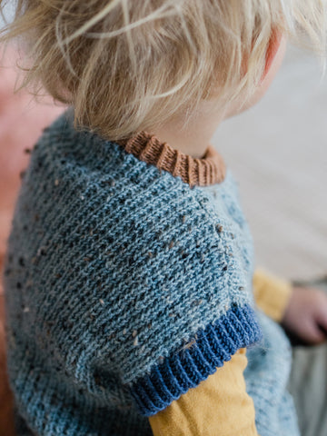 close up photo of hand knit fabric which makes up a blue child sized vest