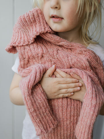 girl holds a hand knit dog sweater