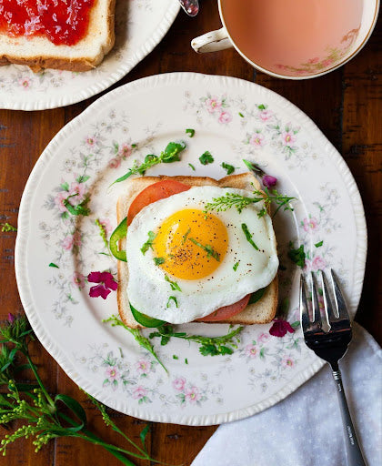 Egg, tomatoes, and herbs on toast, served on a white, flowerly place