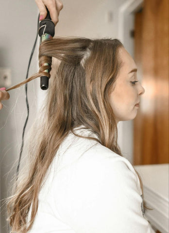 A girl with a longer style kitty cut getting her hair styled with a curling wand. Source: Pexels