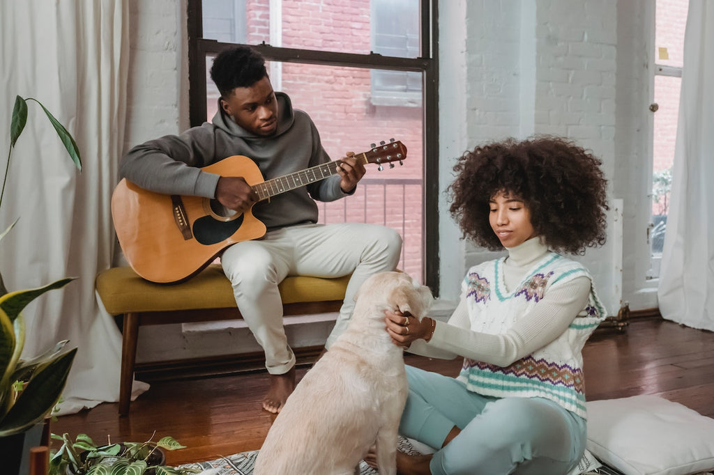 A man calming down a stressed dog with a guitar