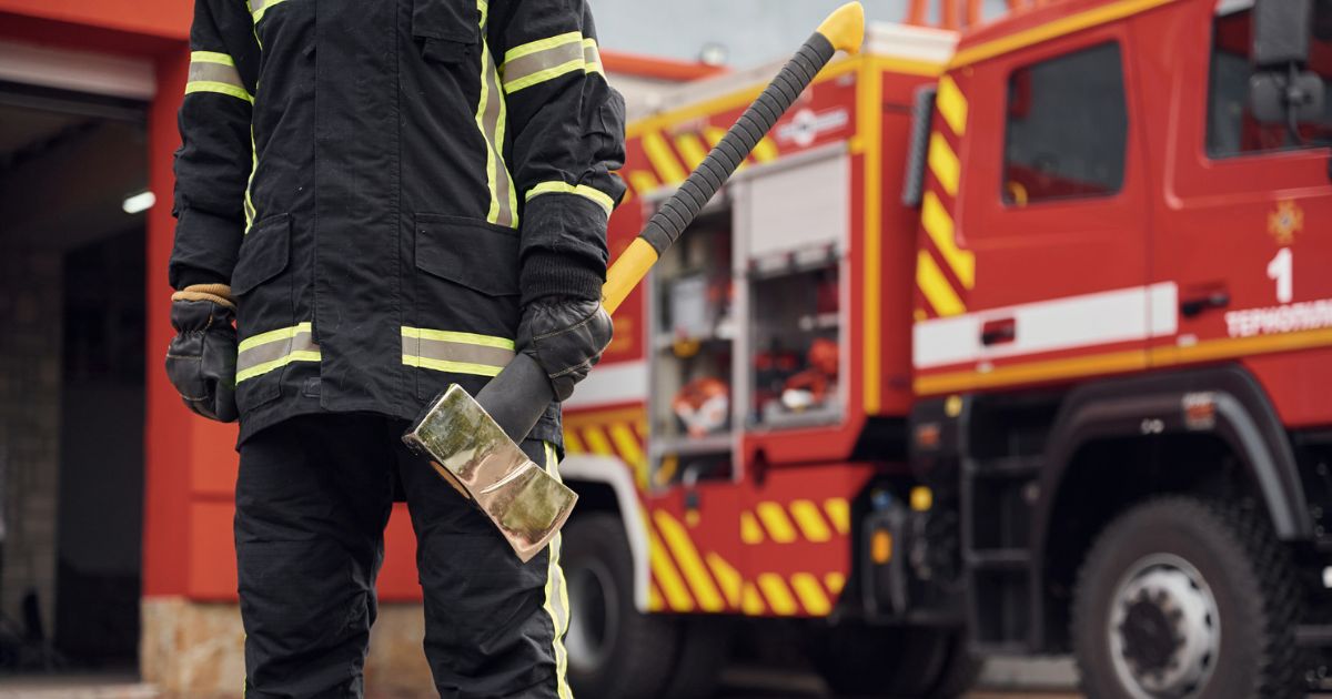 firefighter with axe in front of fire truck