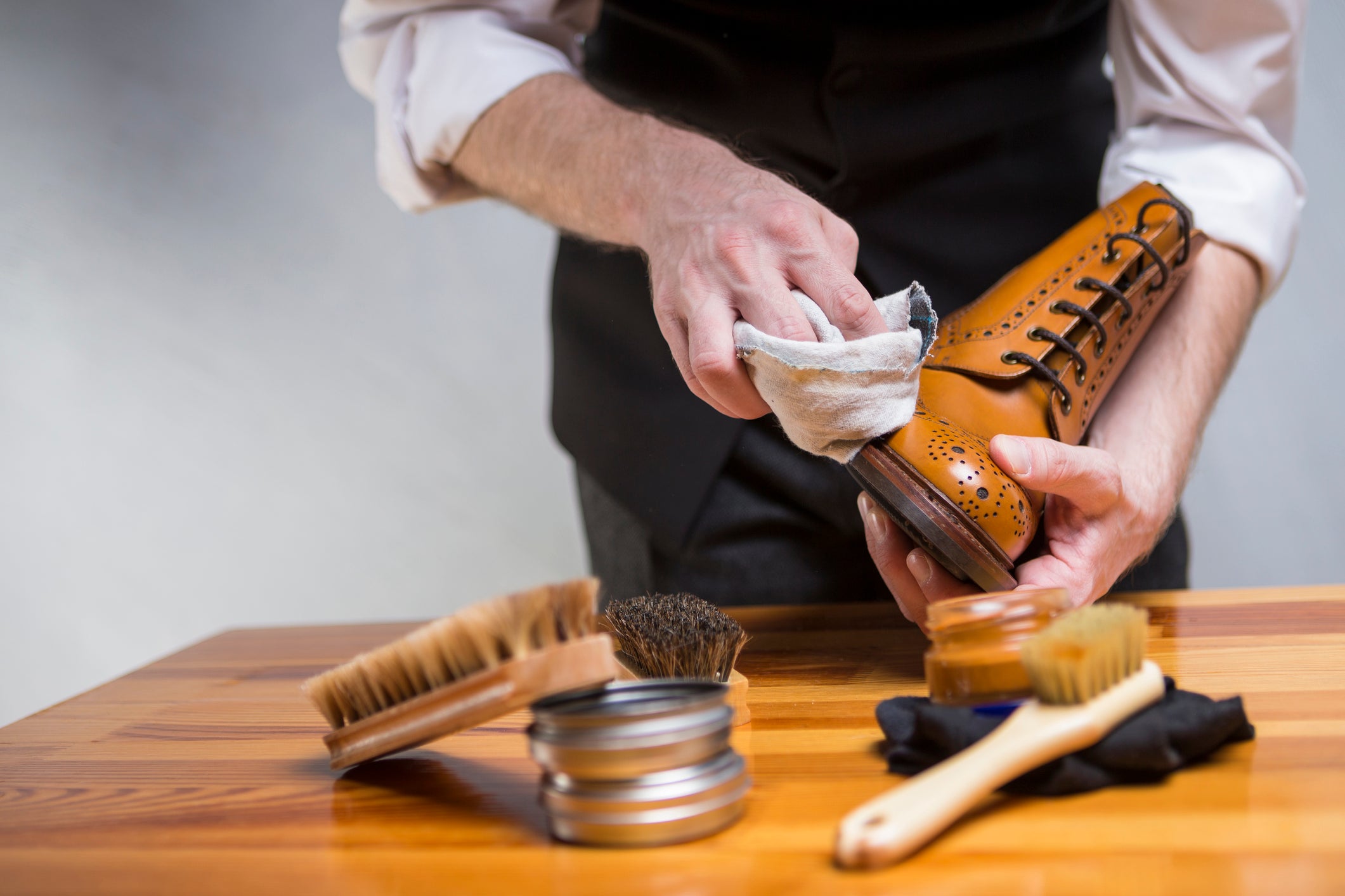 Man polishing brown boots on table