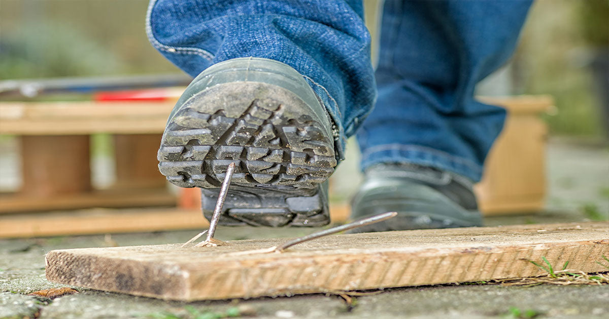 Man wearing work boots stepping on nail