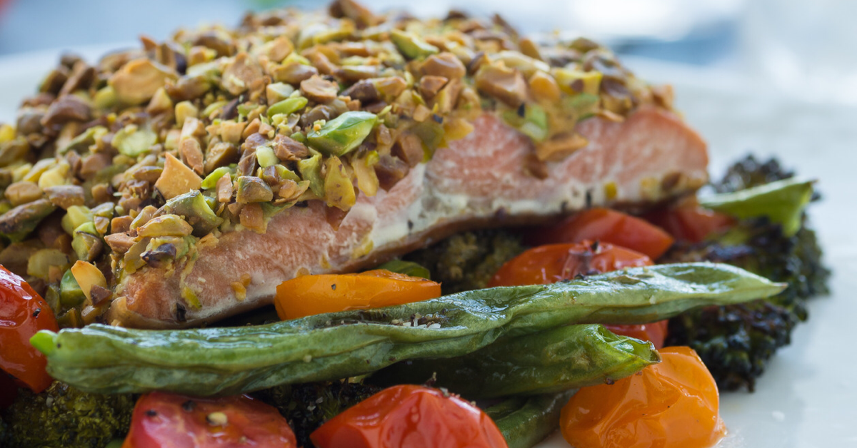 Pistachio crusted salmon on a bed of roasted cherry tomato halves and roasted asparagus