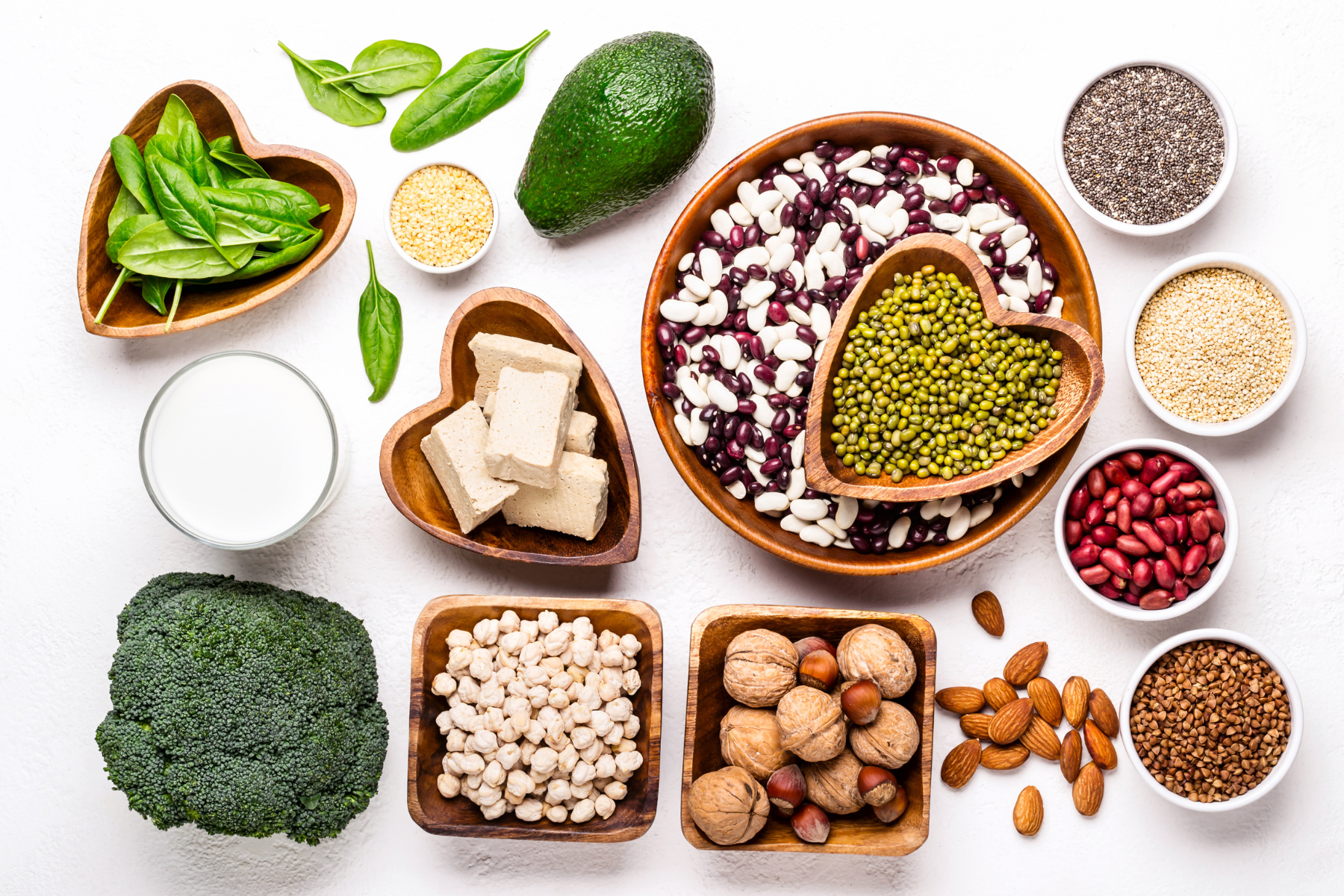 A white table full of estrogen boosting foods such as chickpeas, cruciferous vegetables, nuts, cheese and milk.