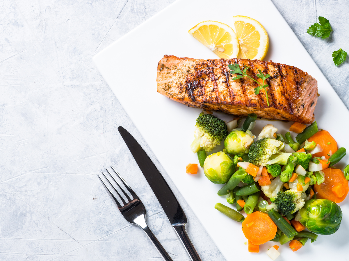 A healthy lunch as part of a Paleo diet meal plan consisting of grilled salmon and a side of steamed mixed veg.