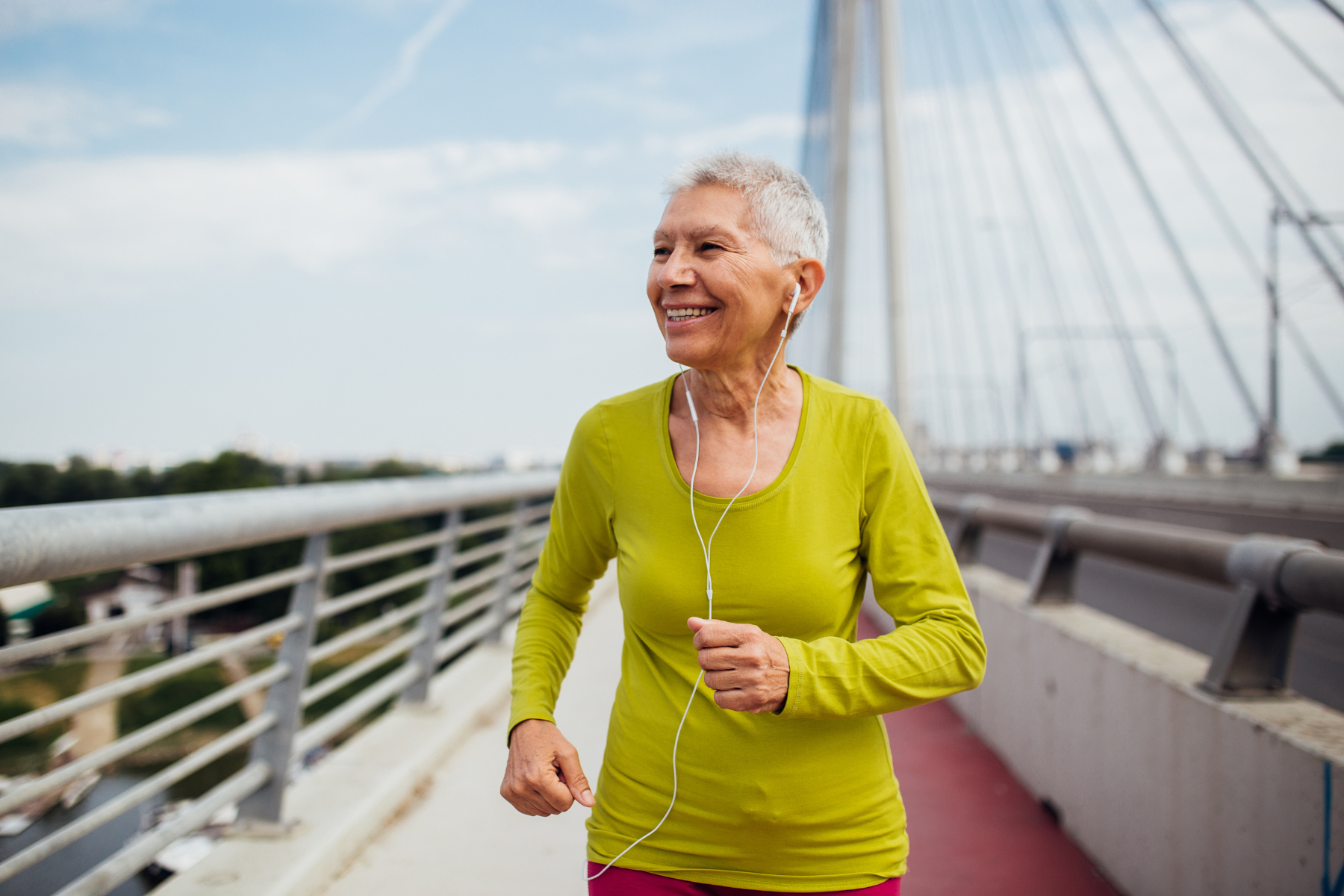 A woman jogging on a bridge, enjoying her exercise routine and staying active.