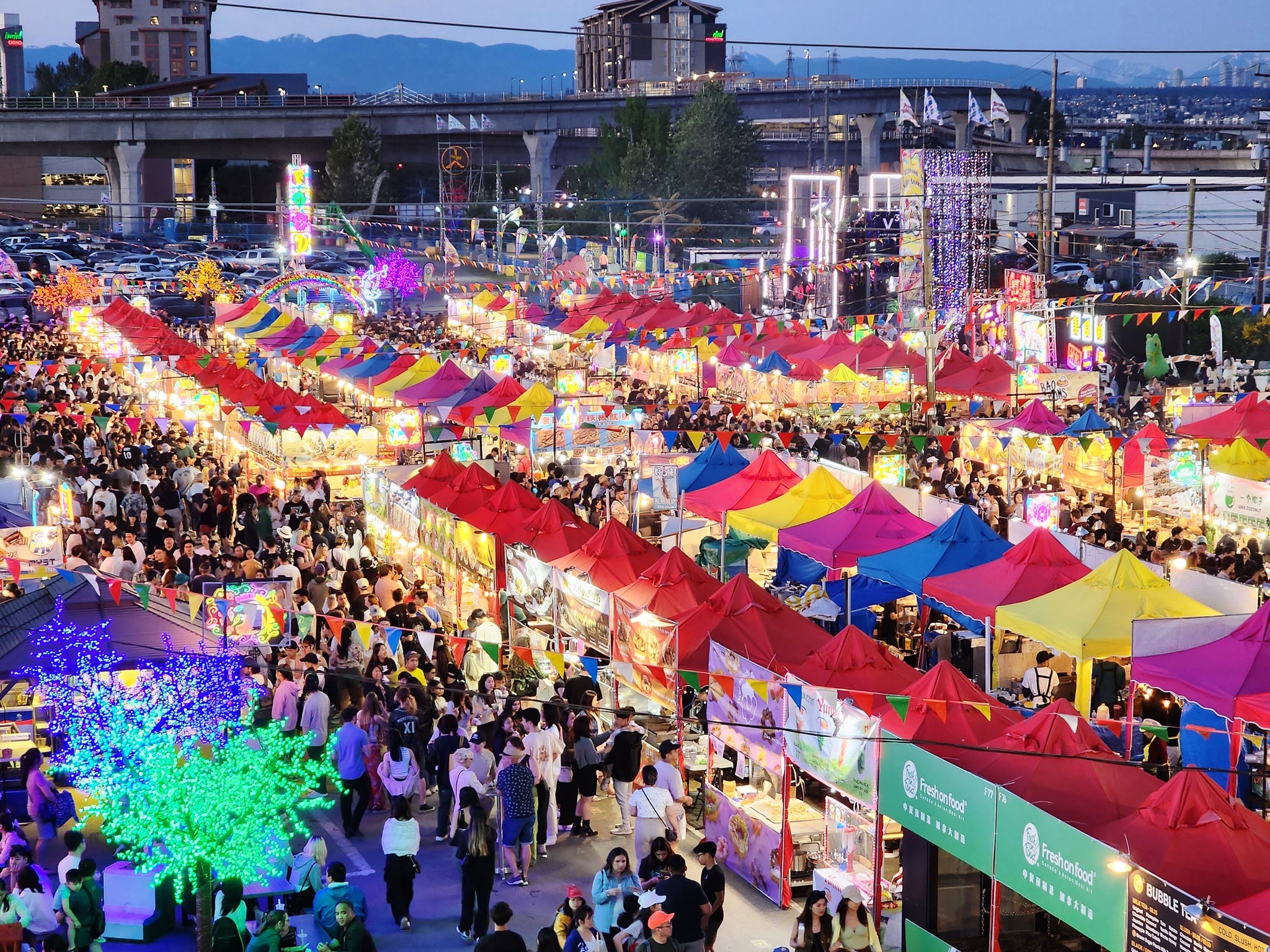 A large crowd enjoys the lively ambiance of the Richmond Night Market, filled with various stalls and outdoor activities.