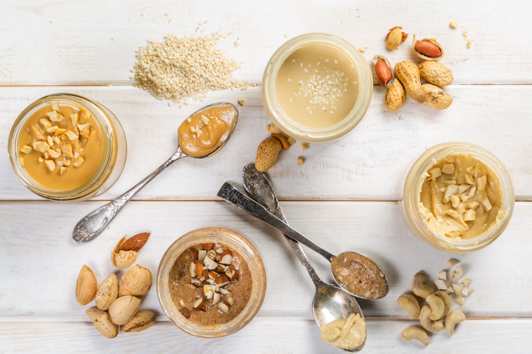 A variety of nut butters including peanut, almond, and cashew butter, displayed in a jar.