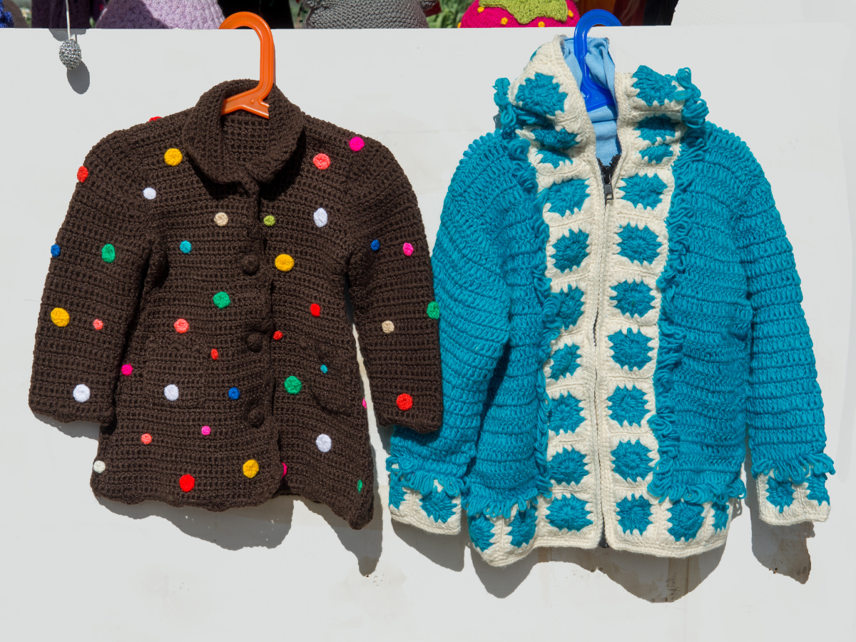 A pair of artisan cardigans elegantly hanging on a clothesline, showcasing their unique textures and colors in the sunlight.