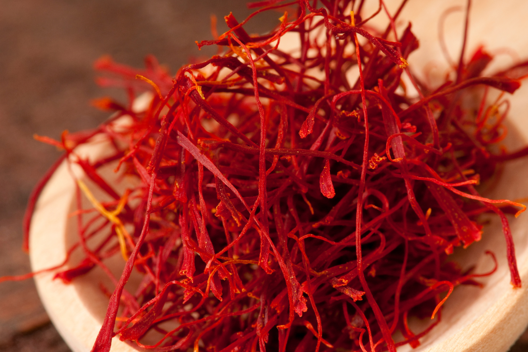 A wooden spoon filled with high quality red saffron, adding vibrant color and flavor to dishes.