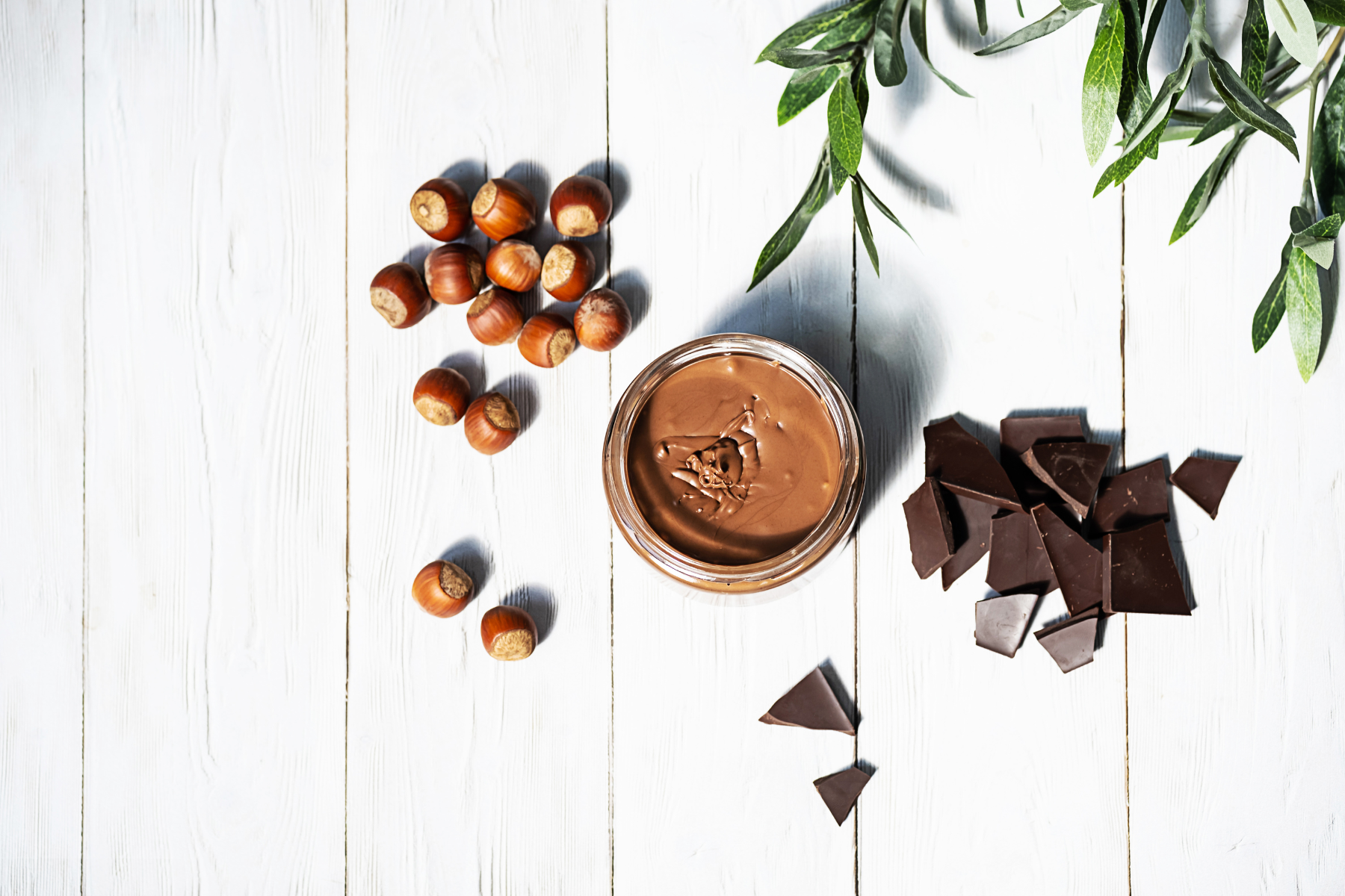 Chocolate hazelnut spread on white wooden table.