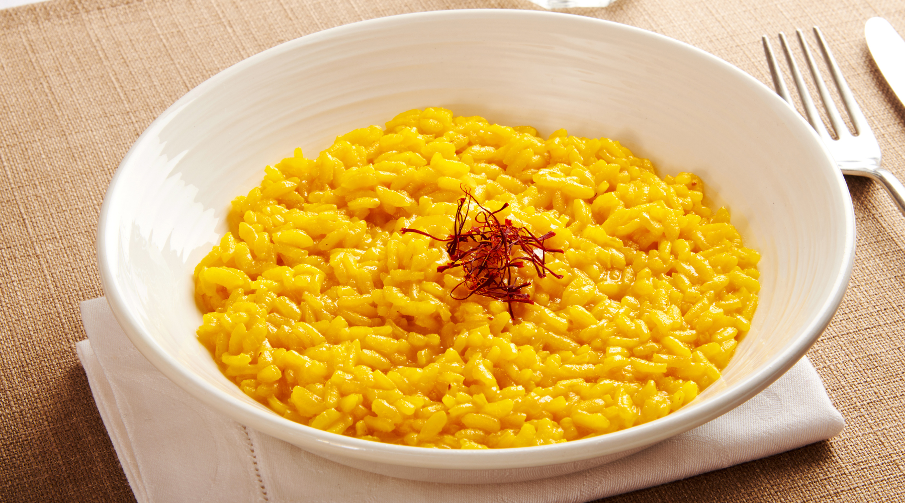 A white bowl filled with saffron rice, a vibrant yellow dish that is visually appealing and appetizing.