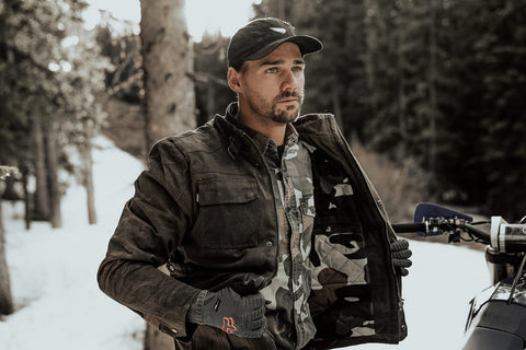 man wearing a warm motorcycle jacket while standing in the snow