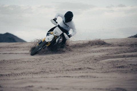 man wearing saint motorcycle top skidding in sand