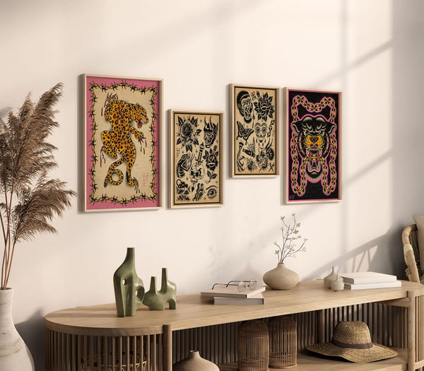 Cream wall with 4 different sized frames with art prints sold by shiverarts.com. 2 larger A3 frames with tattoo style large, wild cats and the middle 2 A4 frames have a traditional blackwork flash art prints on stained paper.