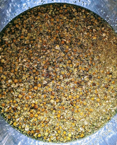 bird's eye view of a metal vat full of chamomile flowers floating in water