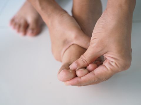 A person rubbing their foot to ease the chronic foot pain caused by diabetic neuropathy
