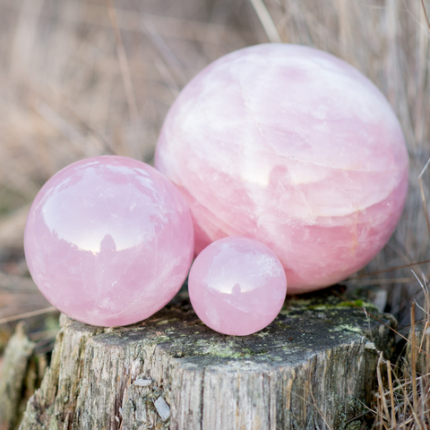 rose quartz sphere, pink rose quartz sitting on wood outside