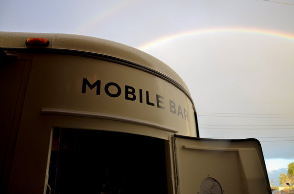 the top front portion of the horsetrailer we turned into a mobile bar, in front of an out of focus double rainbow.