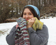 30-something white woman is hugging various knit samples close to her face, and she is smiling.