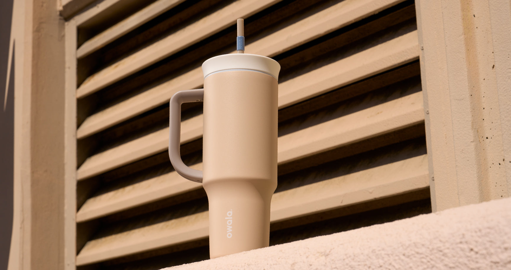 tan colored tumbler in front of tan blinds