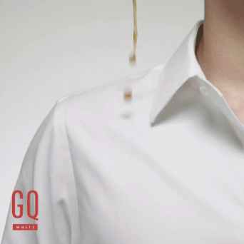 Motion image of coffee being poured on a GQWhite™ shirt and repelling away from the fabric. The rest of the coffee is washed away with water.