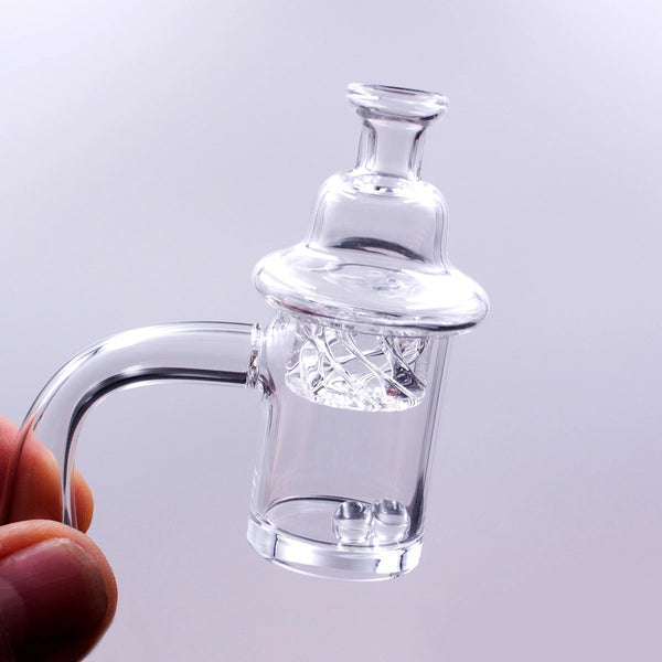 Person is holding a spiraled helix carb cap on top of a quartz banger. The quartz banger has two terp balls inside.